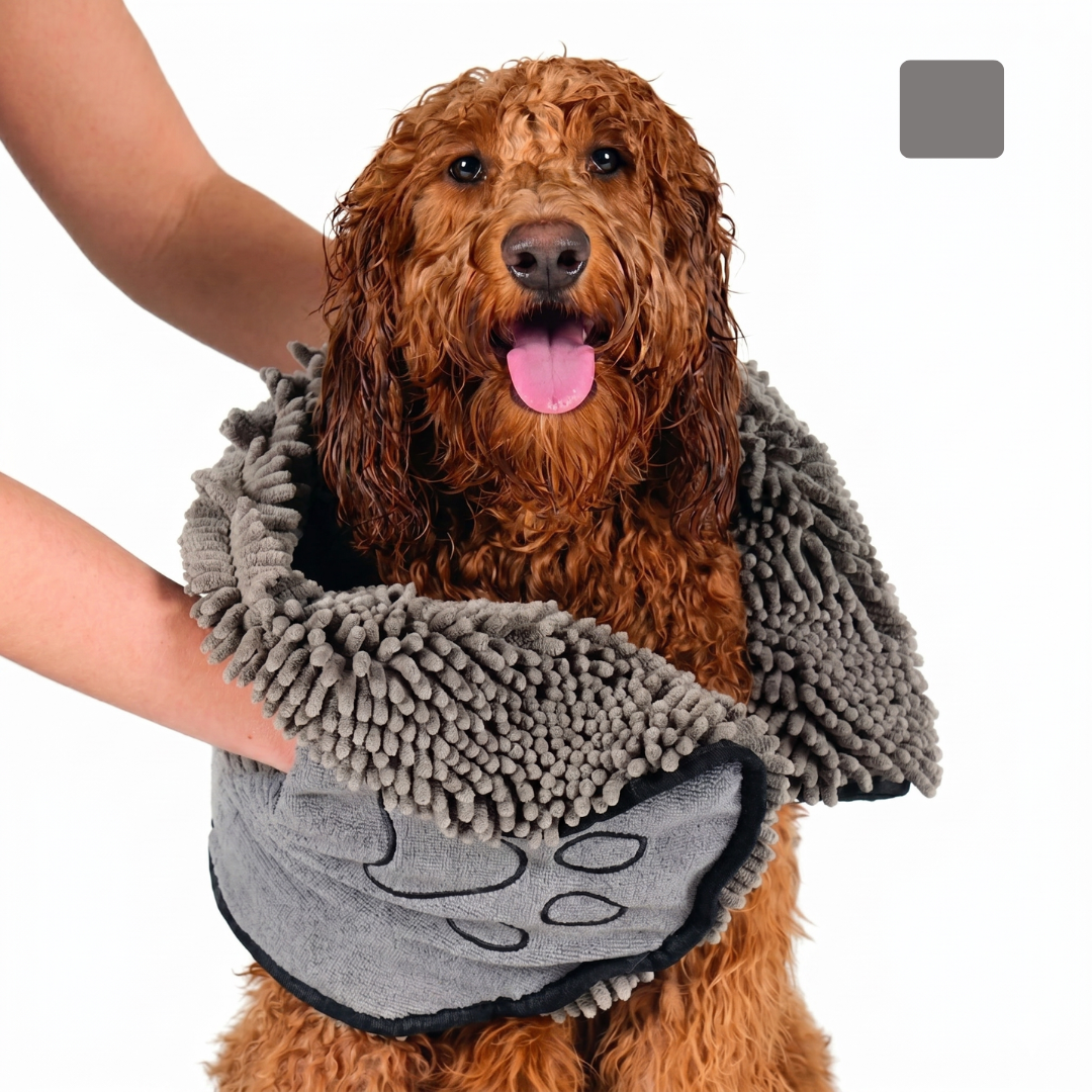 Dog wrapped in a gray chenille towel with paw prints, held by a person.